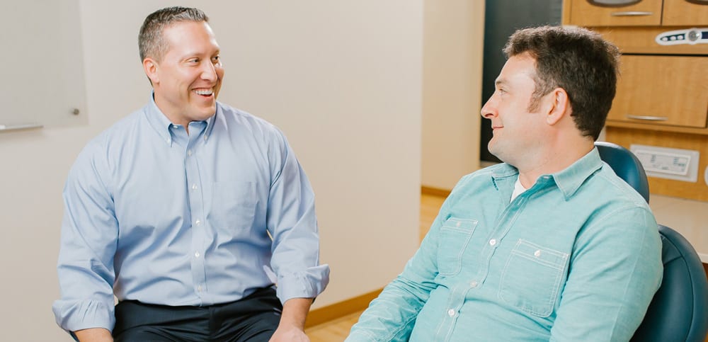 Dr. Jared Cox smiling at an adult patient sitting in a dental chair